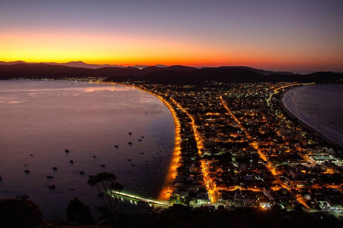 Cidade iluminada à noite vista do alto do morro